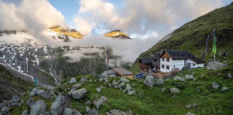 Hiker looks at mountain peaks with last sunlight