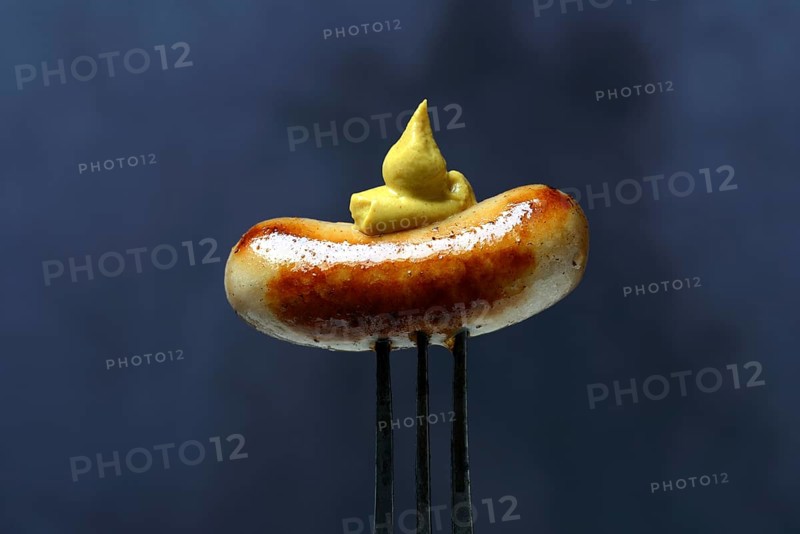 Chipolata sausages with mustard on fork