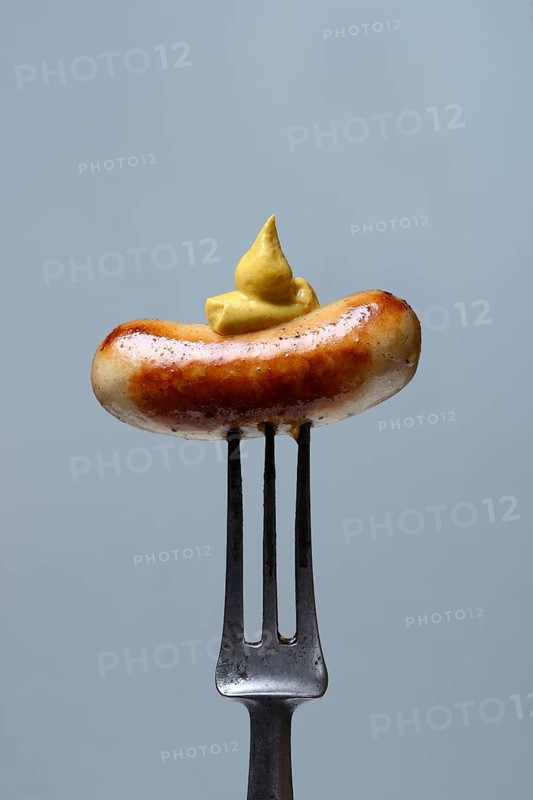 Chipolata sausages with mustard on fork