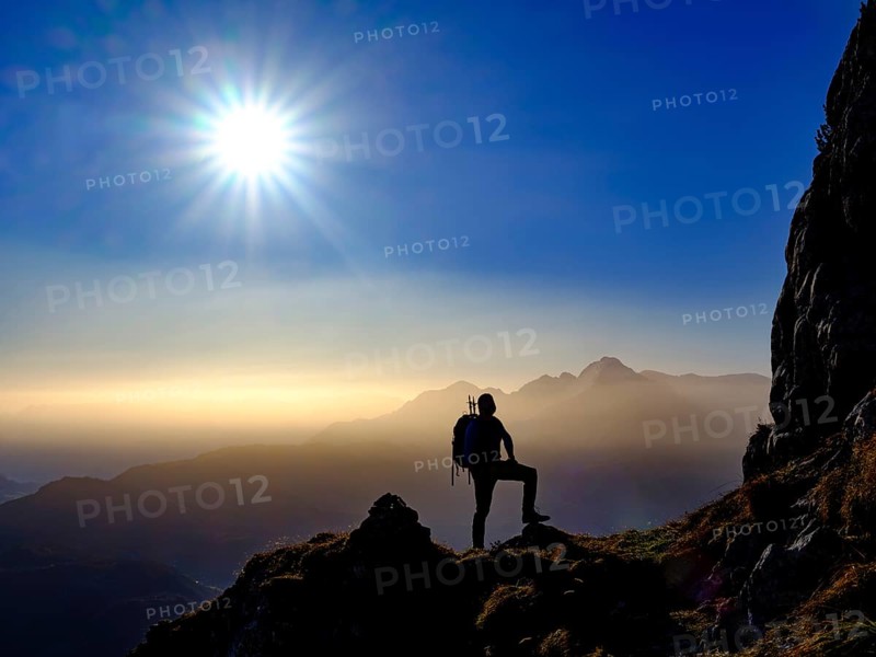 Silhouette of a mountaineer on an exposed path in the morning sun
