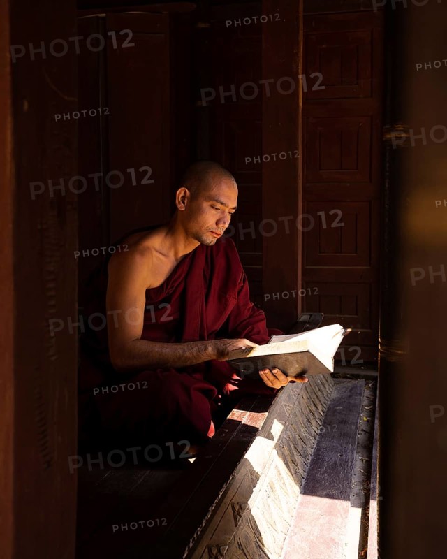 Buddhist monk in red robe reading ancient scriptures in a pagoda