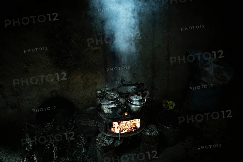 Teapots with milk tea on an oven with blazing embers
