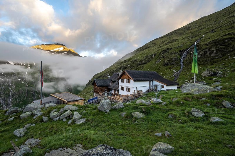 Furtschaglhaus with mountain peaks in the last sunlight and clouds