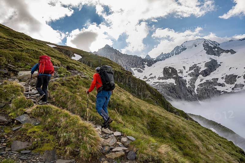 Hikers in front of snow-covered mountain peaks