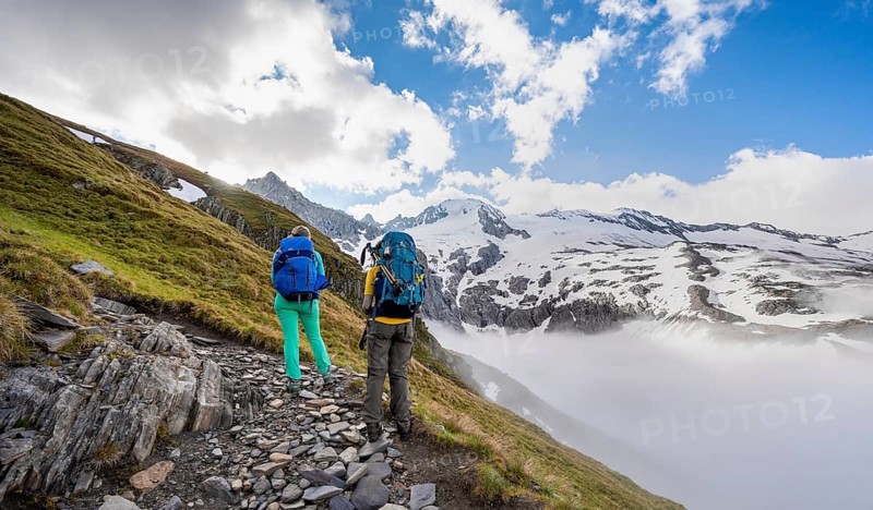 Hikers in front of snow-covered mountain peaks