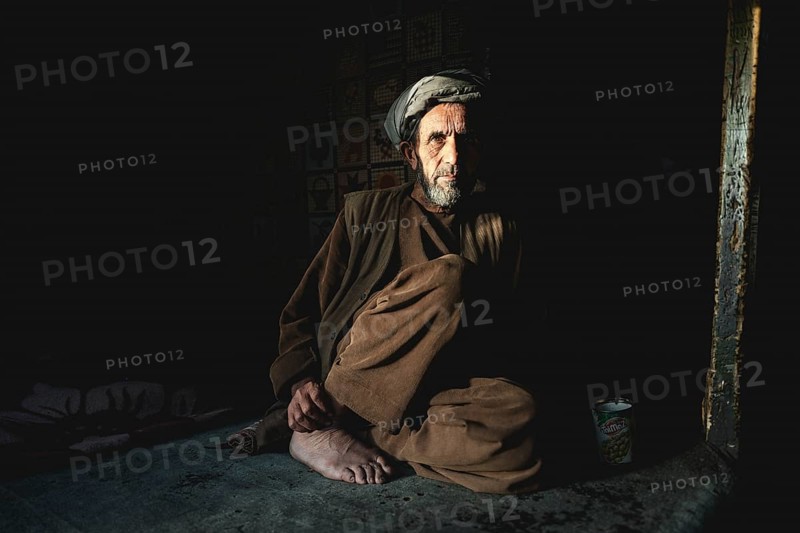 Shopkeeper sitting in the semi-darkness on the floor of his shop
