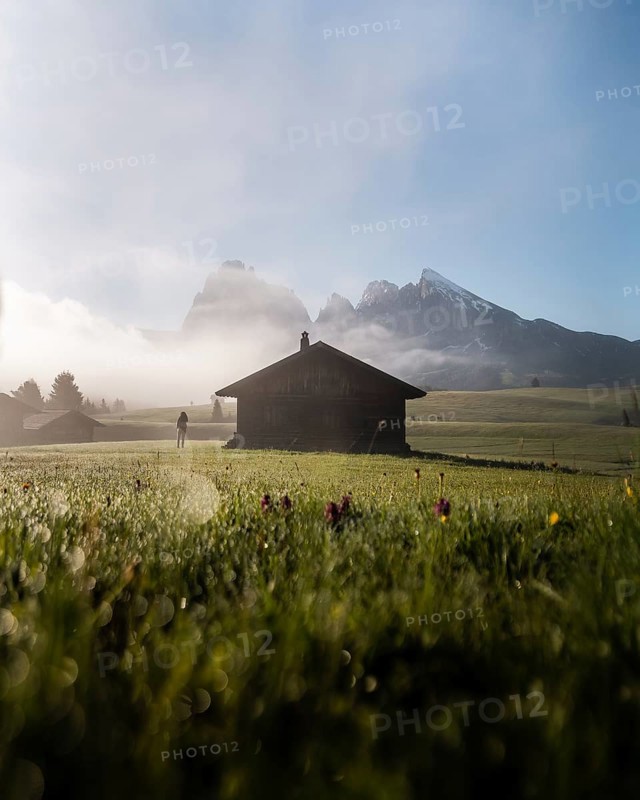 Woman looking on foggy meadow next to hut