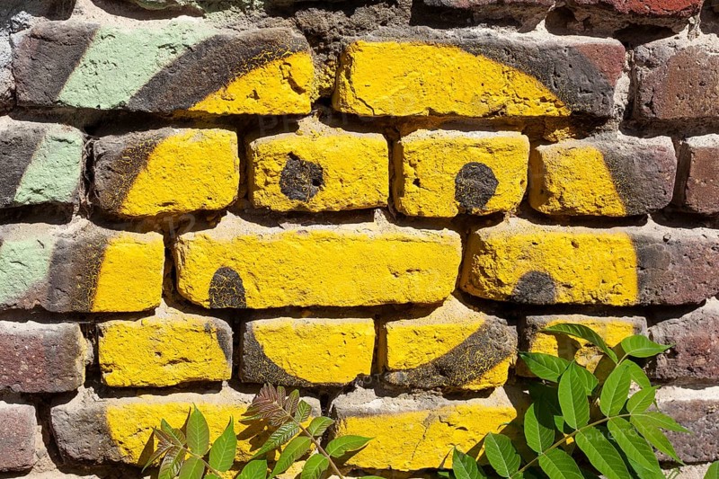 Yellow smiling smiley painted on a brick wall