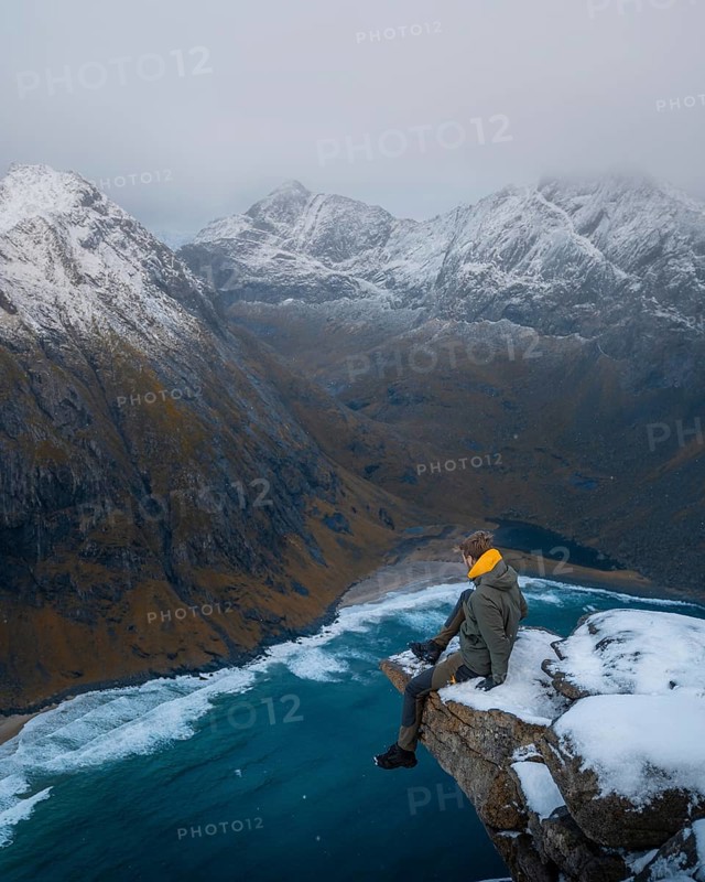 Man sitting on a viewing platform on a mountain in front of Kvalvika beach