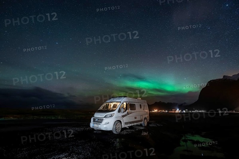 Campervan stands at Uttakleiv beach with northern lights