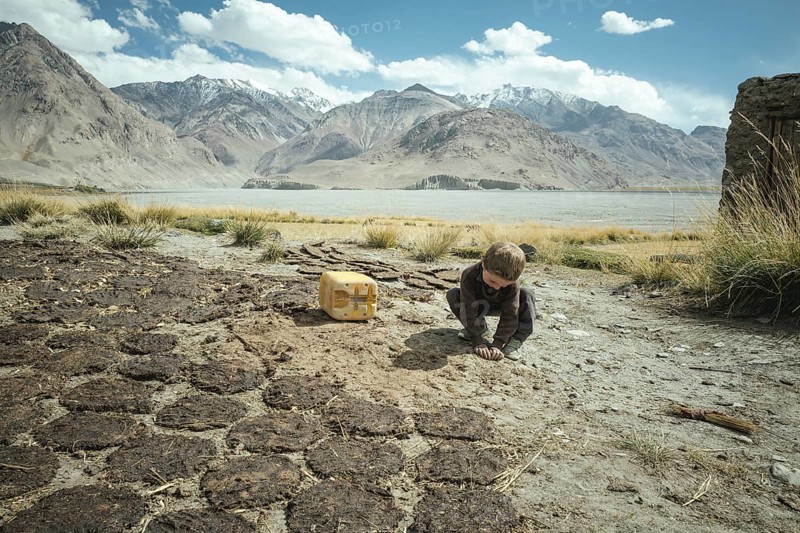 Boy plays next to cow dung flat cakes