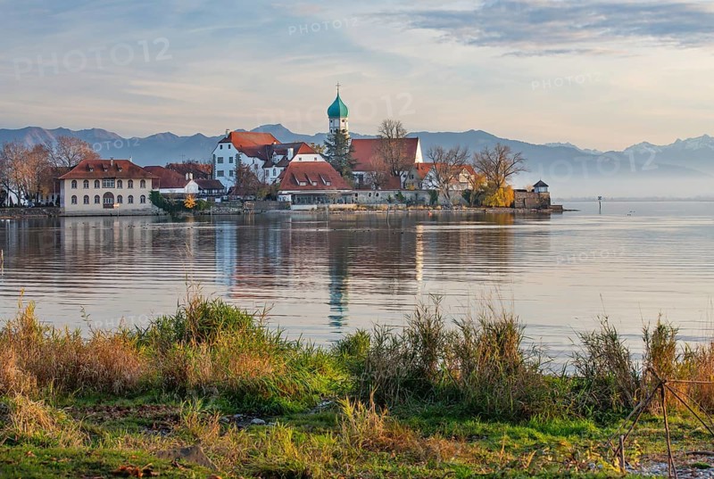 Peninsula with the parish church of St. George in front of the Alps in the evening sun