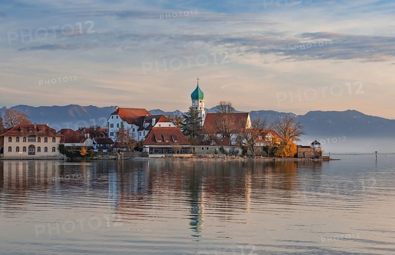 Peninsula with the parish church of St. George in front of the Alps in the evening sun