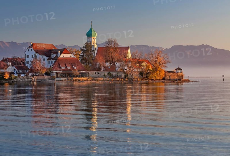 Peninsula with the parish church of St. George in front of the Alps in the evening sun
