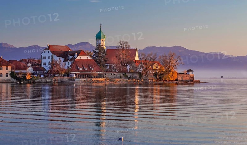 Peninsula with the parish church of St. George in front of the Alps in the evening sun