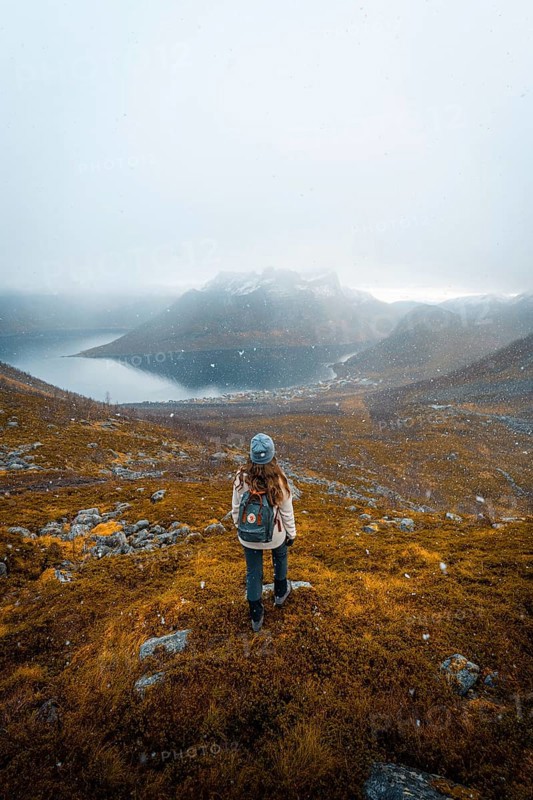 Woman looking at the village Fjordbotn and a prominent and pointed mountain