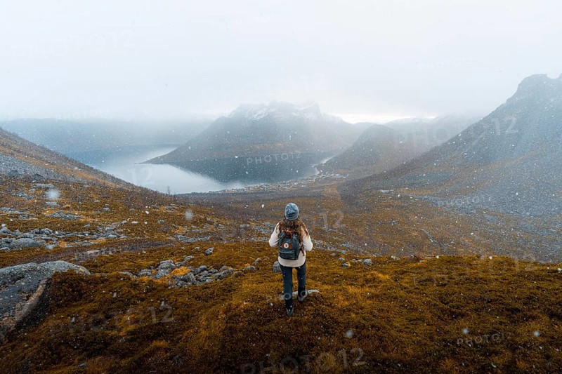 Woman looking at the village Fjordbotn and a prominent and pointed mountain