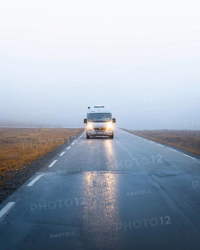 Campervan with bright lights on a road near the North Cape