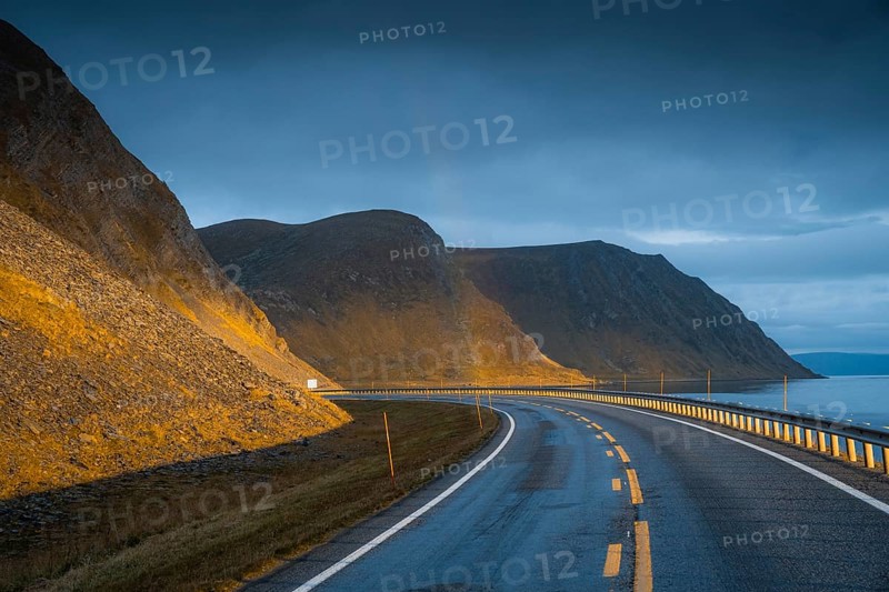 Road leading to rainbow with dramatic sky and sunset light
