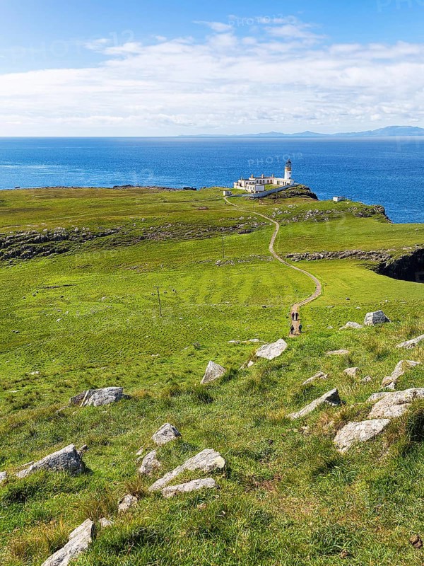 Hiking trail to the lighthouse on the Neist Point peninsula with views of the Outer Hebrides on the horizon