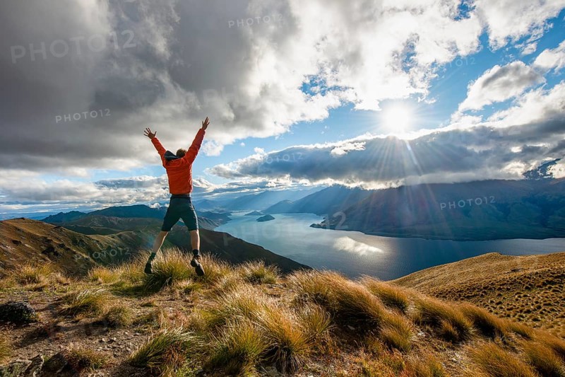 Hiker stretches his arms in the air and takes a leap in the air