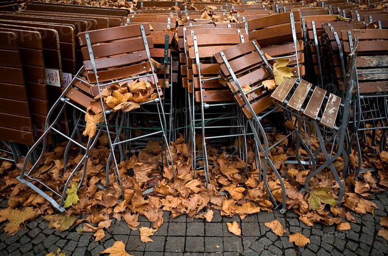 Tables and chairs of a closed beer garden in autumn leaves