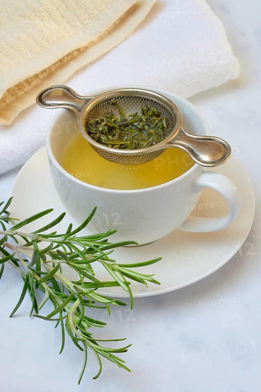 A cup of rosemary tea with tea strainer