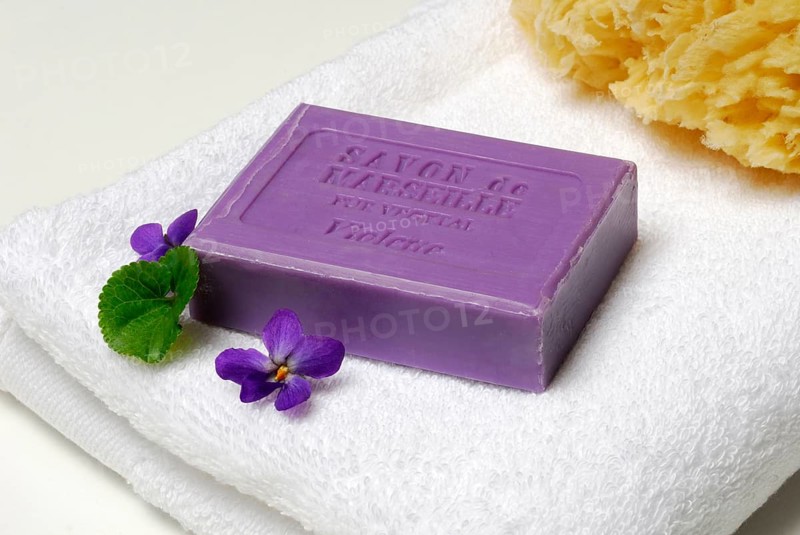 Violet soap and violet flowers on towel