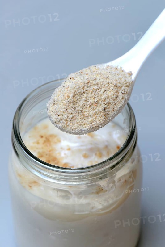 Tigernut flour in spoon and glass yoghurt