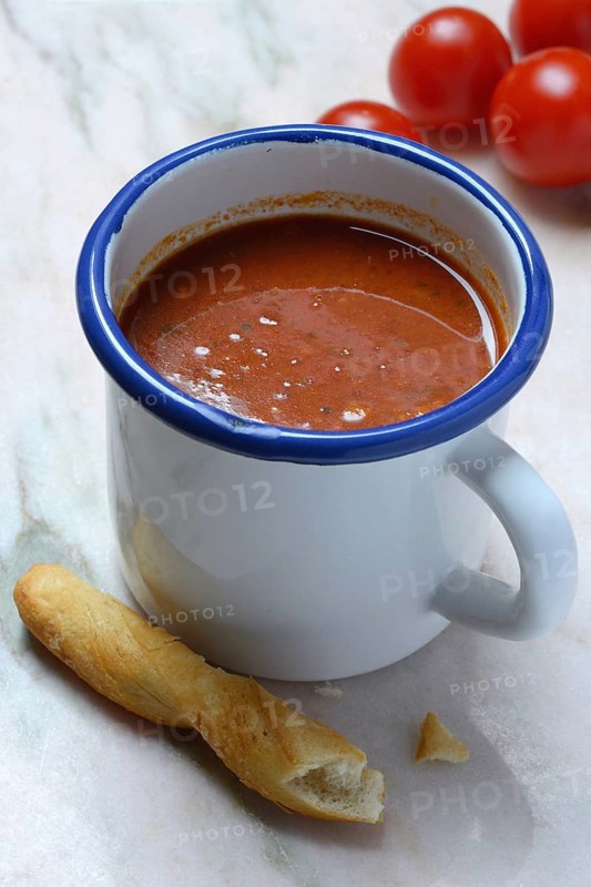 Tomato soup in cup with breadstick and tomatoes