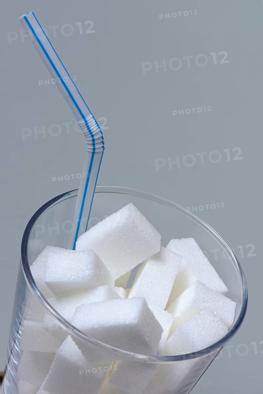 Sugar cubes in drinking glass with straw