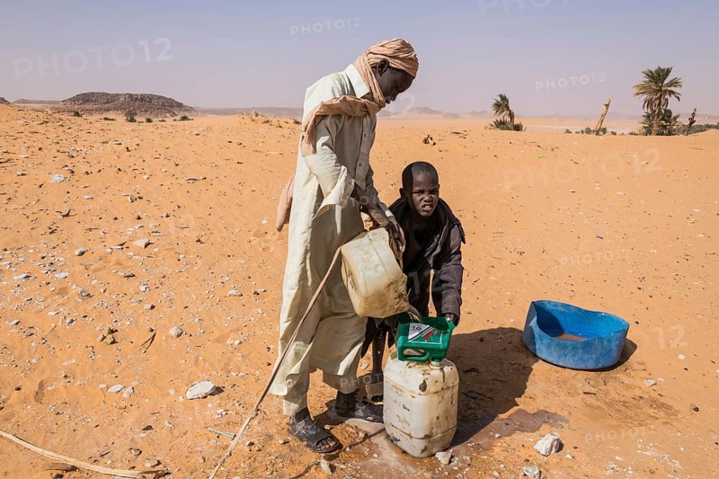 Local boys pulling out water out of a well in the desert