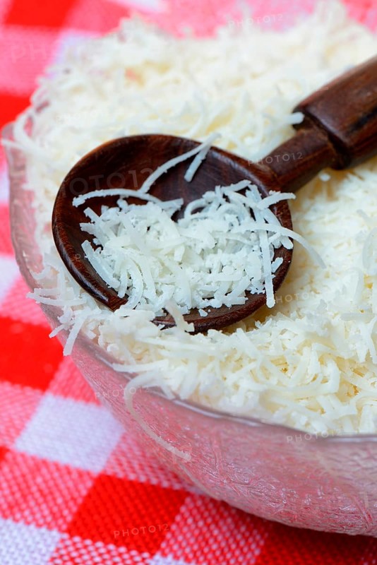 Grated Parmesan cheese in glass bowl with wooden spoon