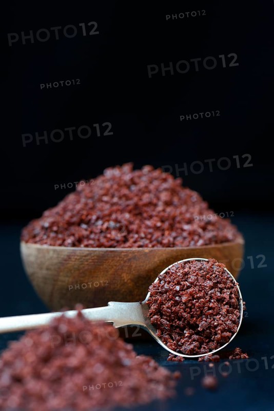 Sumac powder in wooden bowl and spoon