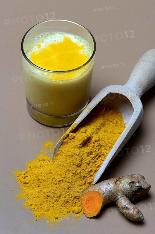 Turmeric-powder in shovel and -milk in glass