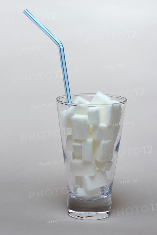 Sugar cubes in drinking glass with straw