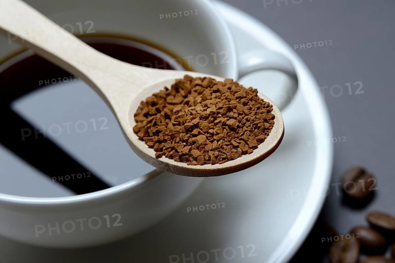 Instant coffee in spoon on coffee cup