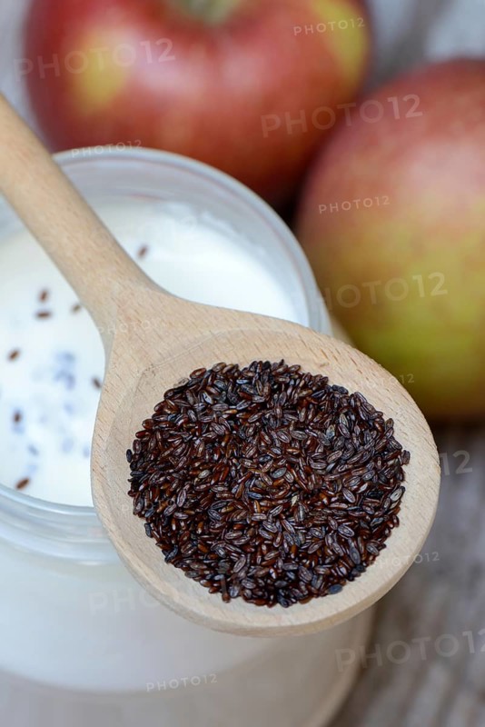Psyllium plantain in cooking spoon on yoghurt glass and apples