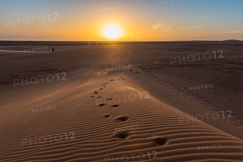 Footsteps in a sand dune at sunset