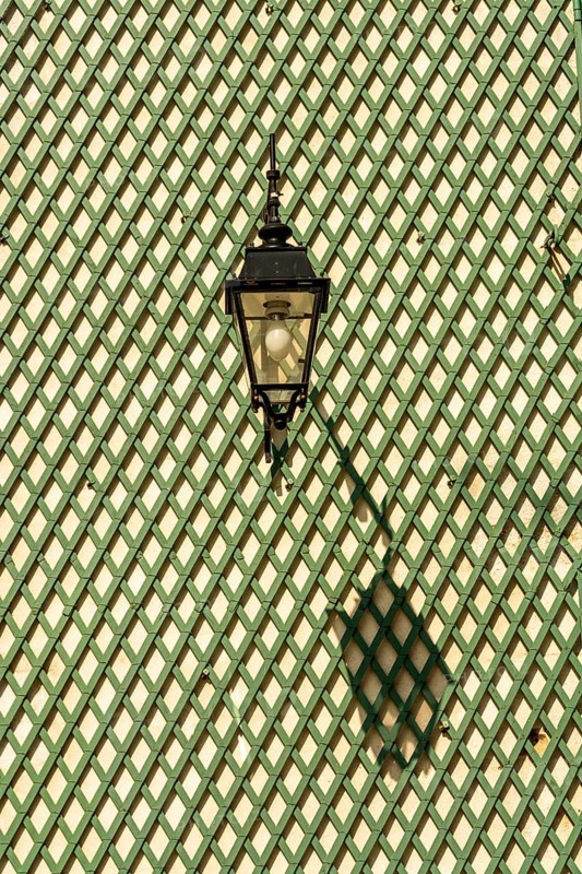 Shadow of a lantern on a green wooden lattice wall