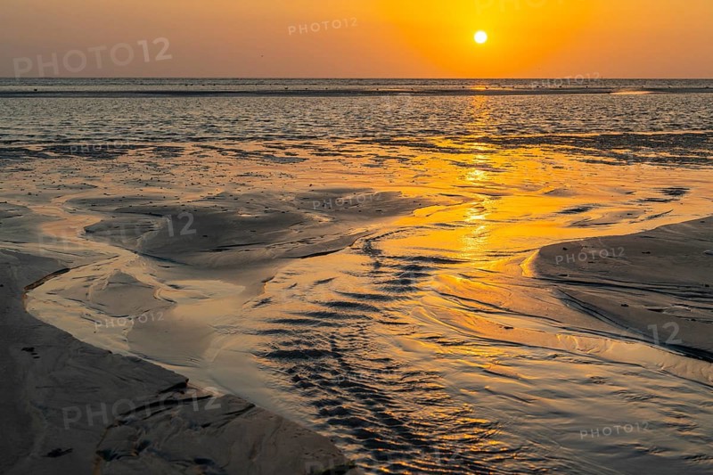 Sunset over tidal creek on sandy beach