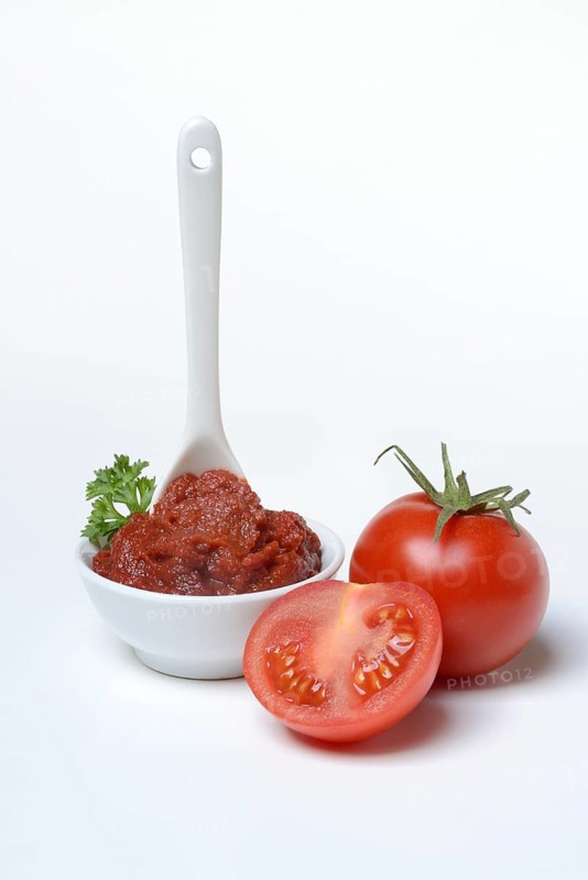 Tomato paste with spoon in bowl