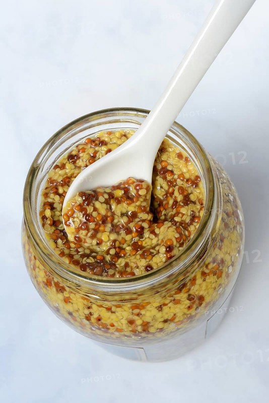 Grainy mustard in glass with spoon