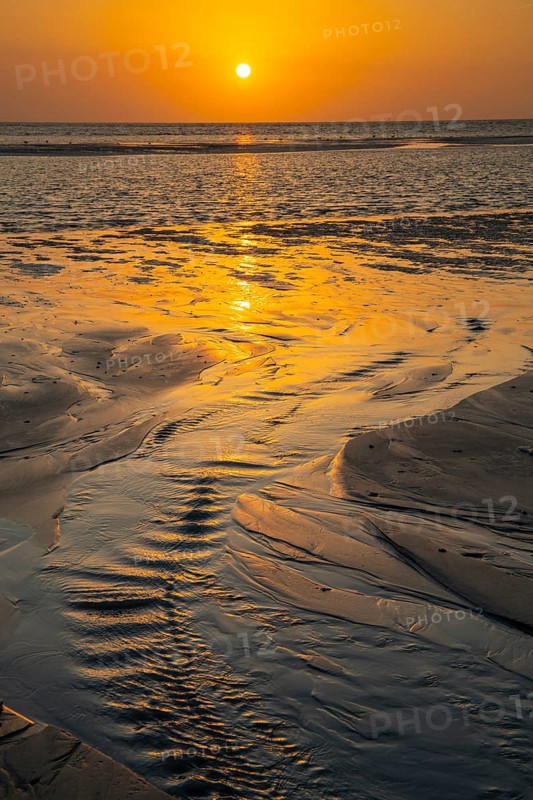 Sunset over tidal creek on sandy beach