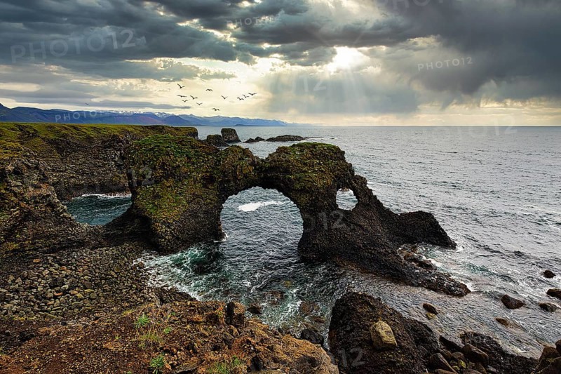 Eroded cliff at the Atlantic Ocean with Gatklettur and dramatic cloud formation