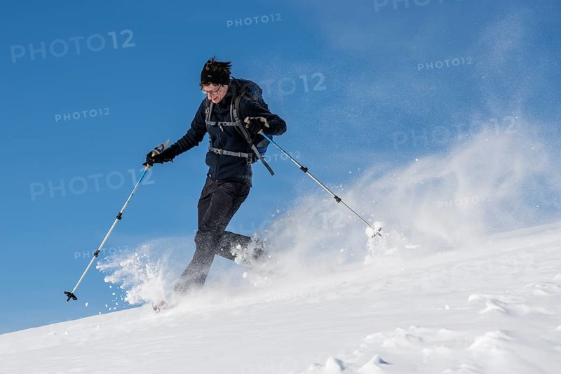 Woman with snowshoes walking through snow