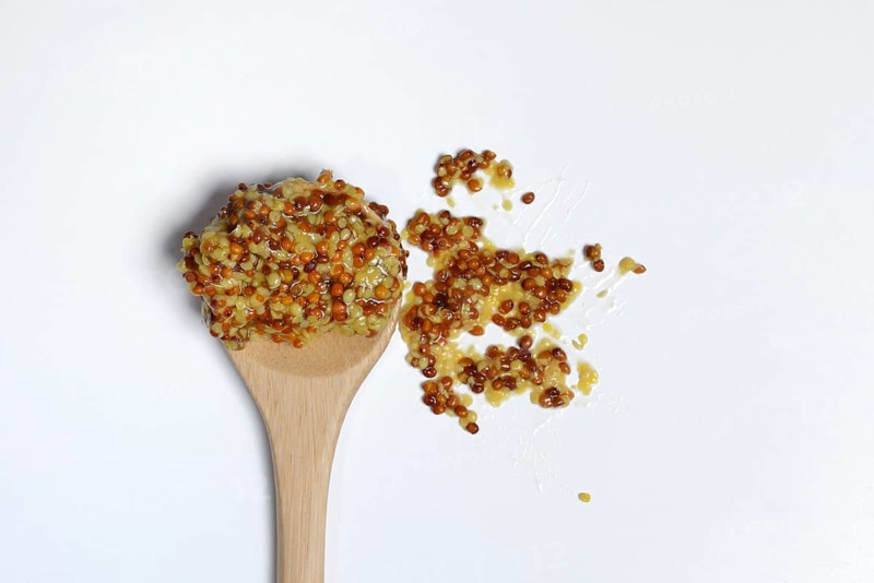 Grainy Dijon mustard on wooden spoon