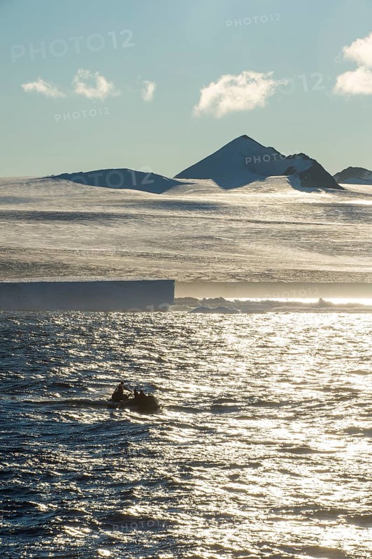 Backlight of a Zodiac with tourists cruising through the icebergs