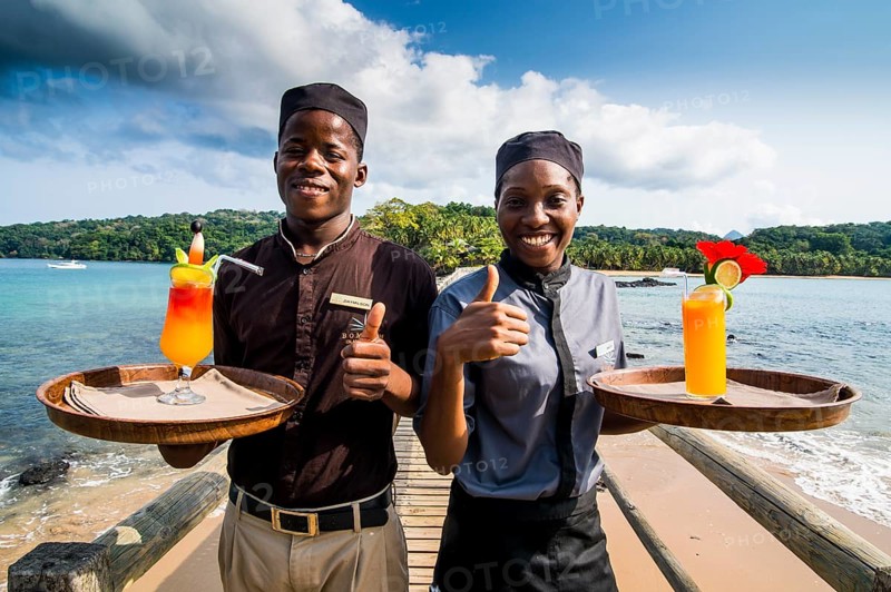 Waiters serving cocktails on a long wooden pier in the Bom Bom Resort