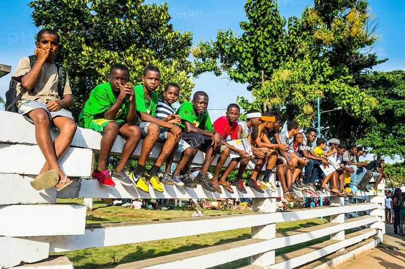 Boys on a wall watching the Carneval parade in the town of Sao Tome